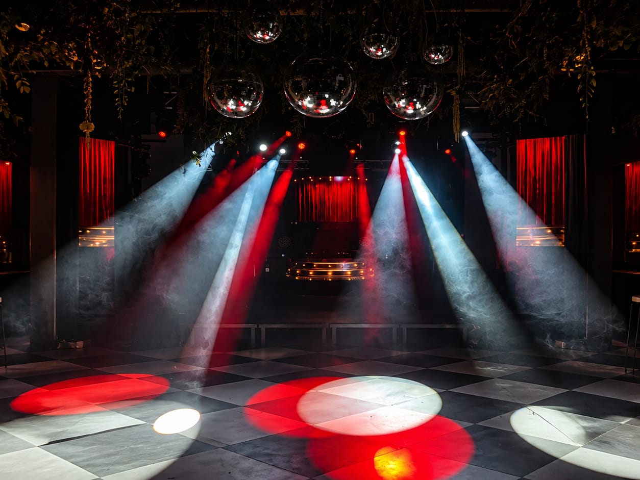 Pista de baile iluminada con focos de color y bolas de espejos, lista para una fiesta